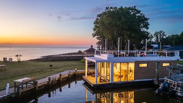 A waterfront house with a dock, a covered outdoor seating area, and a view of the water.