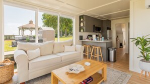 A modern living room with a sofa, a wooden coffee table, and a view of the outdoors.