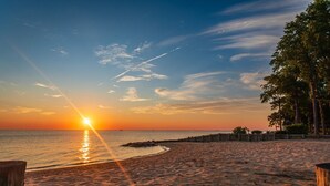 A beach with a wooden boardwalk, ocean view, and trees.