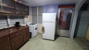 Una cocina compacta con estufa a gas, un refrigerador blanco y un mueble de madera.