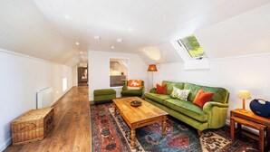 A spacious living room with a green sofa, a wooden coffee table, and a patterned rug. - The Byre, Countryside Home (Tough)