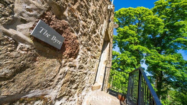 A stone wall with a plaque reading "The Bye." - The Byre, Countryside Home (Tough)