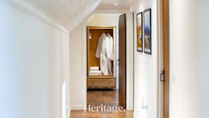 A hallway leading to a room with a wooden wardrobe, a bed, and a framed picture on the wall. - The Byre, Countryside Home (Tough)
