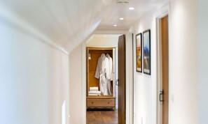 A hallway leading to a room with a wooden wardrobe, a bed, and a framed picture on the wall. - The Byre, Countryside Home (Tough)