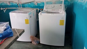 Two white washing machines in a room with blue walls and a concrete floor.