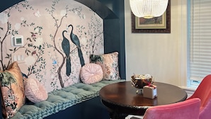 A room with a round table, a chandelier, a blue wall with a tree mural, and a window with blinds. - Stay in the Heart of historic Georgetown! (Georgetown)