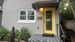 Una casa con una porta gialla, facciata in mattoni e ingresso rivestito di piastrelle decorate.