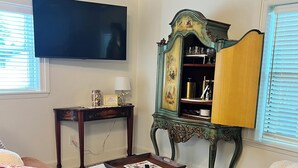Un soggiorno con un divano marrone, un tavolino rotondo, una televisione a parete e un mobile decorativo con vetreria.