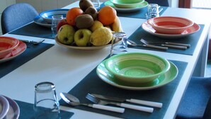 Une table à manger dressée avec des assiettes, des bols et des couverts.