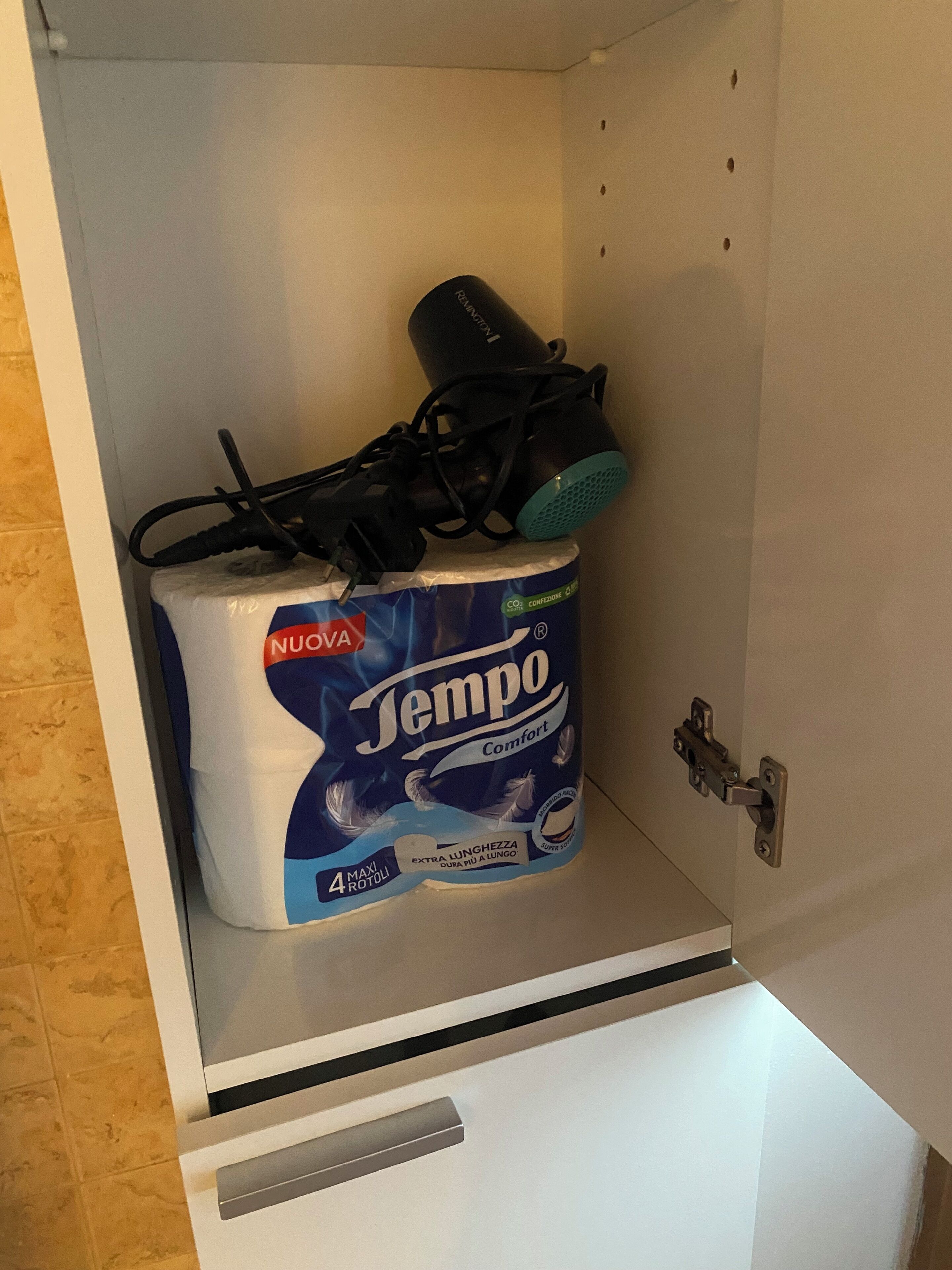 A toilet paper roll labeled 'Tempo Comfort' in a cabinet.