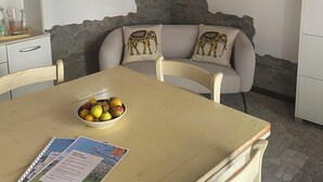 Un comedor acogedor con una mesa, sillas, un cuenco de fruta y una obra de arte enmarcada en la pared.
