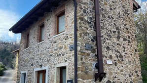 Un edificio de piedra con puerta de madera, ventana y chimenea.
