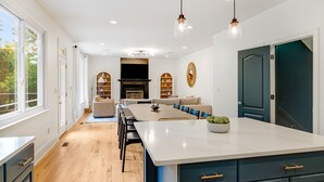 A modern kitchen with a central island, wooden flooring, and built-in cabinetry. - Spacious & Luxe~Hot Tub~Bocce~Fenced Backyard~Mins to Downtown! (Asheville)