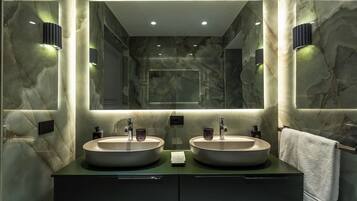 Un baño moderno con dos lavamanos, un espejo grande y paredes de mármol.