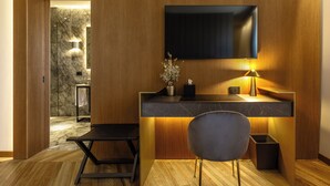 A modern interior with a wooden panel wall, a flat-screen TV mounted above a marble countertop, a small table with a chair, and a potted plant. - Fontart Tritone  (Rome)