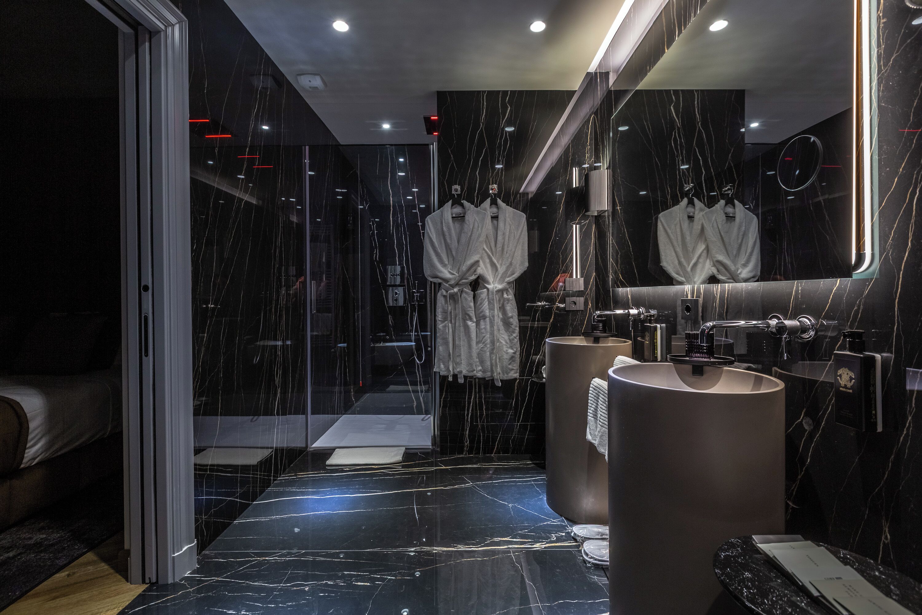 Une salle de bain moderne avec un grand miroir, deux lavabos et une douche à l’italienne.