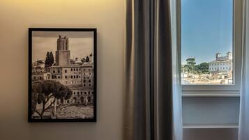 A framed black and white photograph of a historic building with a tower, displayed on a wall next to a window with curtains.