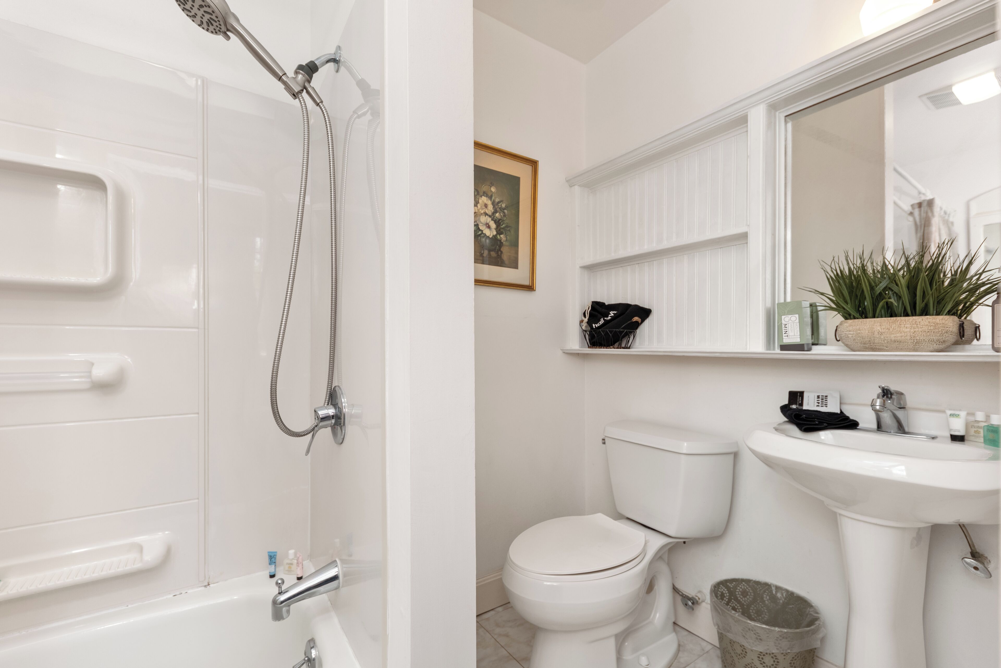 A bathroom with a bathtub, toilet, sink, and a framed picture on the wall.