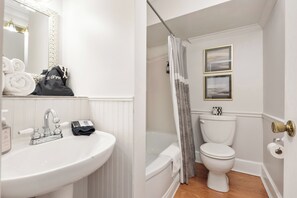 A bathroom with a white sink, a mirror, a toilet, and a shower curtain. - The Benchmark Inn (Augusta)