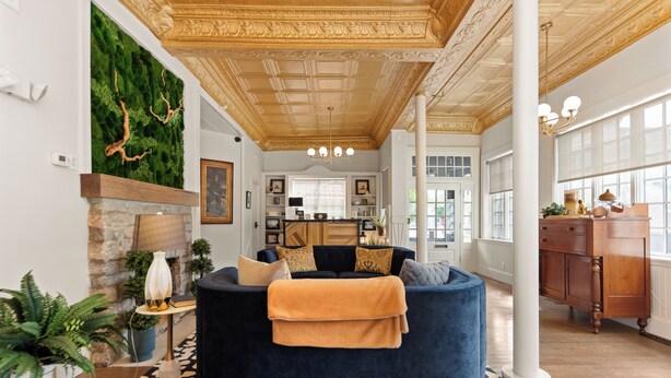 Un salon moderne avec un canapé bleu foncé, un tapis à motifs et un mur décoratif vert.