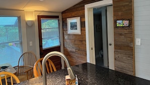 A kitchen with wooden walls, a granite countertop, and a hanging light fixture.
