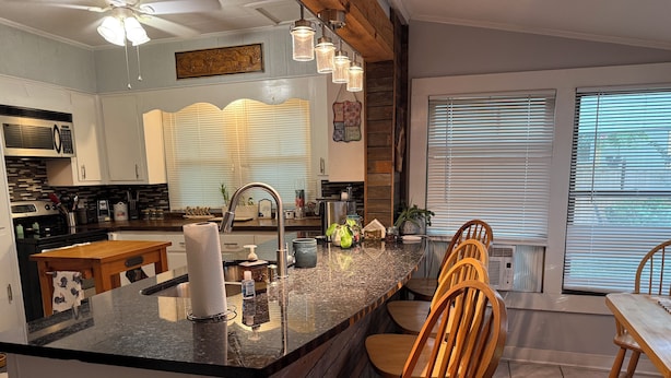 A modern kitchen with a central island, wooden chairs, and a dining table.