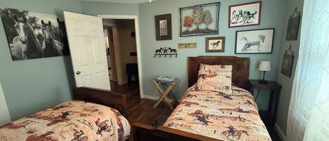 Een slaapkamer met twee bedden, een plafondventilator en diverse decoraties met paardenthema.