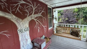 A porch with a painted tree mural, a bench, and a sign that reads "TREE HOUSE".