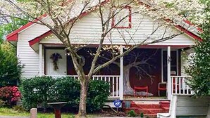 A single-story house with a porch, a small garden, and a wooden fence.