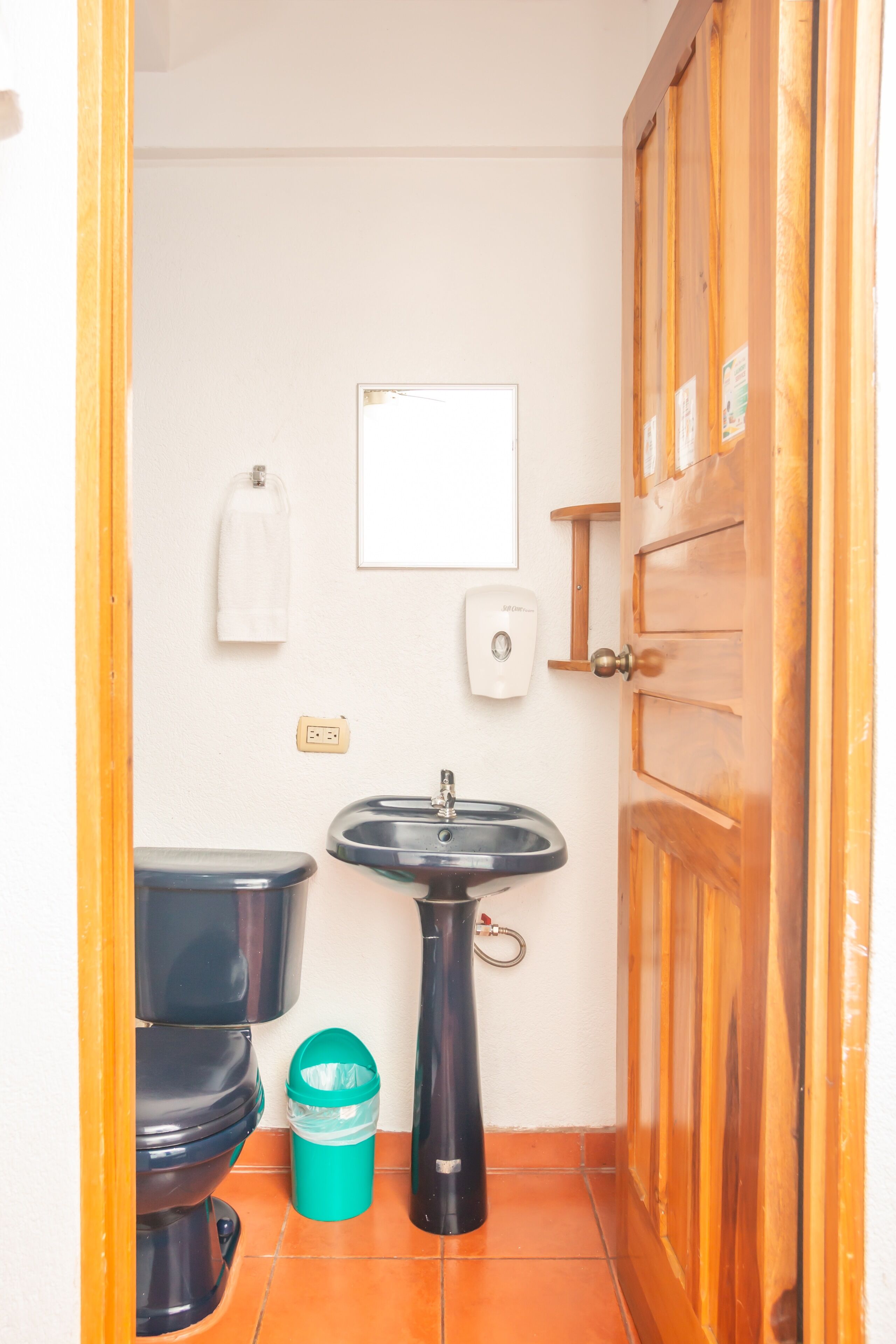 A small bathroom with a toilet, sink, and a wooden door.