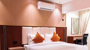 Une chambre d’hôtel moderne dotée d’un grand lit, d’une tête de lit en bois et d’un système de climatisation intégré.