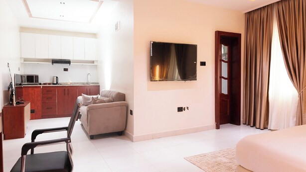 Une chambre d’hôtel moderne équipée d’un lit, d’un bureau, d’une chaise, d’un canapé, d’un téléviseur à écran plat et d’un coin cuisine.