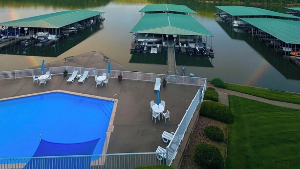 A marina with green-roofed docks and a swimming pool with lounge chairs.