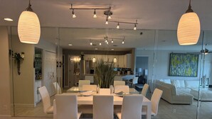 A modern kitchen with white cabinets, a stainless steel refrigerator, and a dining area with a white table and chairs.