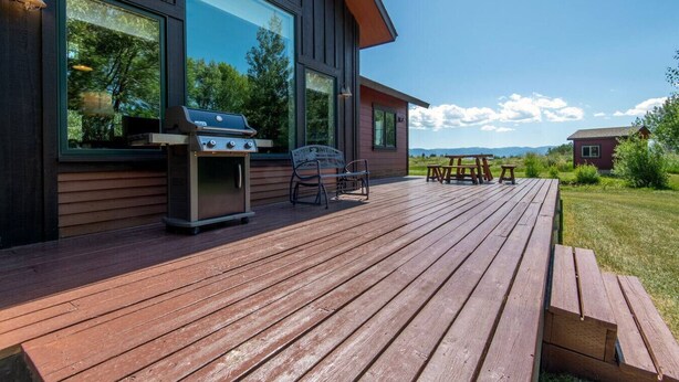 Une maison moderne dotée d’une terrasse en bois, d’un barbecue et d’un espace salon extérieur.