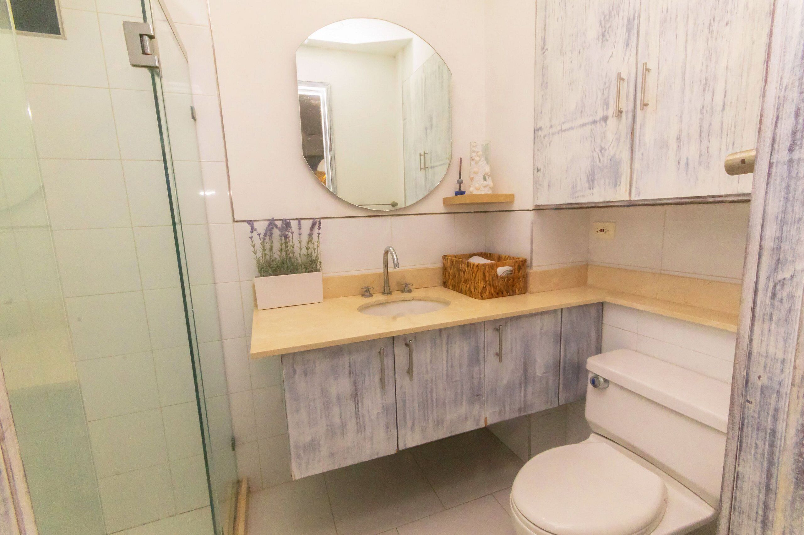 Ein Badezimmer mit Duschkabine, Waschbecken und Spiegel sowie Toilette.