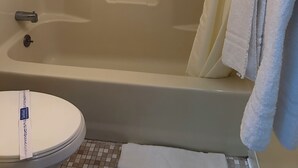 A bathroom with a bathtub, toilet, and a towel rack. - Bedford Motel  (Bedford)