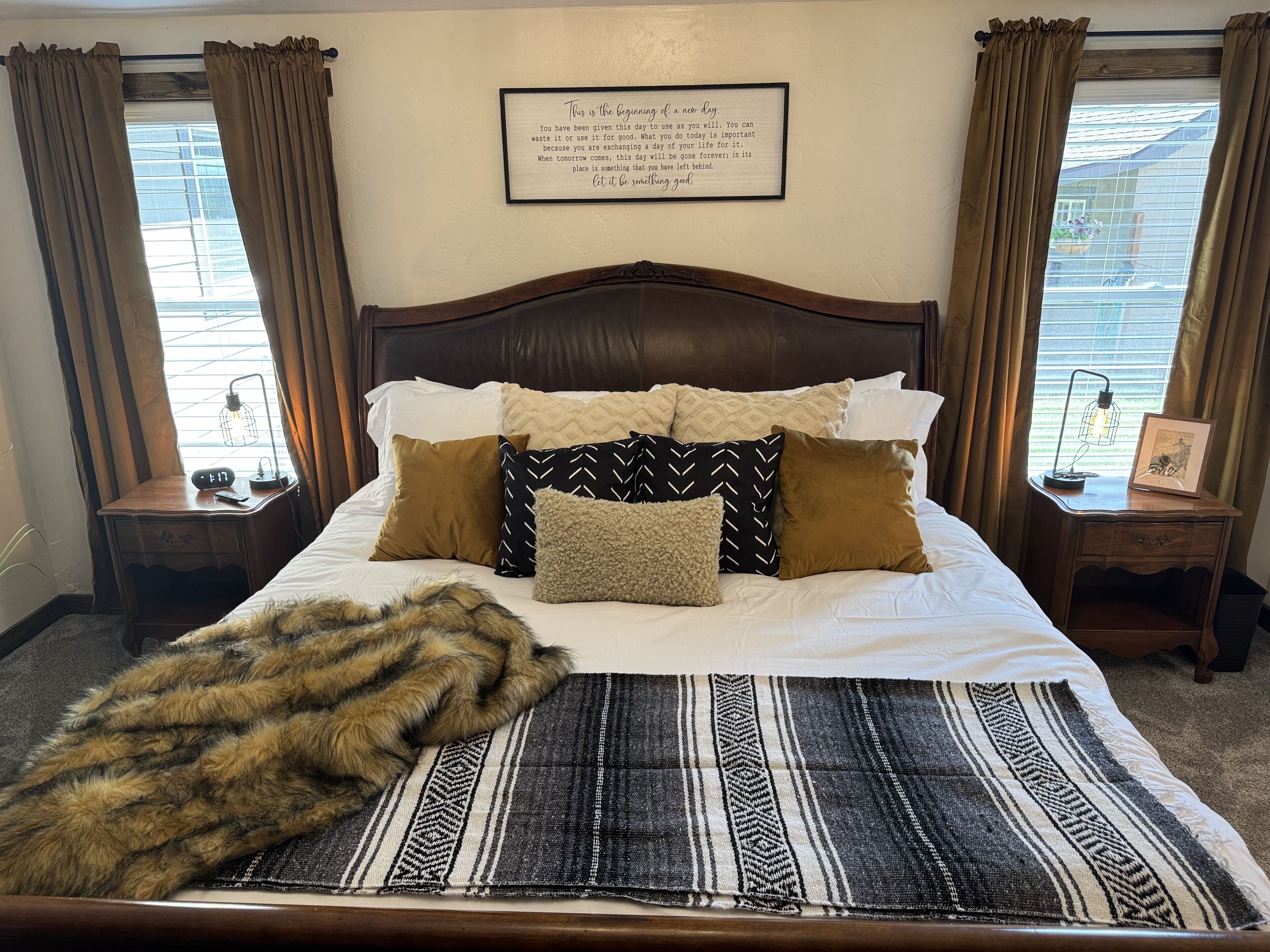 A neatly made bed with a variety of pillows, a throw blanket, and a framed inspirational quote on the wall.