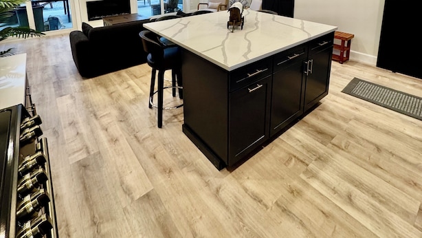 A modern kitchen with a large island, black cabinetry, and a view of the outdoors through large windows. - House in tranquil Tamworth NH with AC, Hot Tub, Riverfront access (Tamworth)