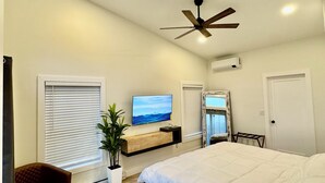 A bedroom with a large bed, a ceiling fan, a TV, and a potted plant. - House in tranquil Tamworth NH with AC, Hot Tub, Riverfront access (Tamworth)