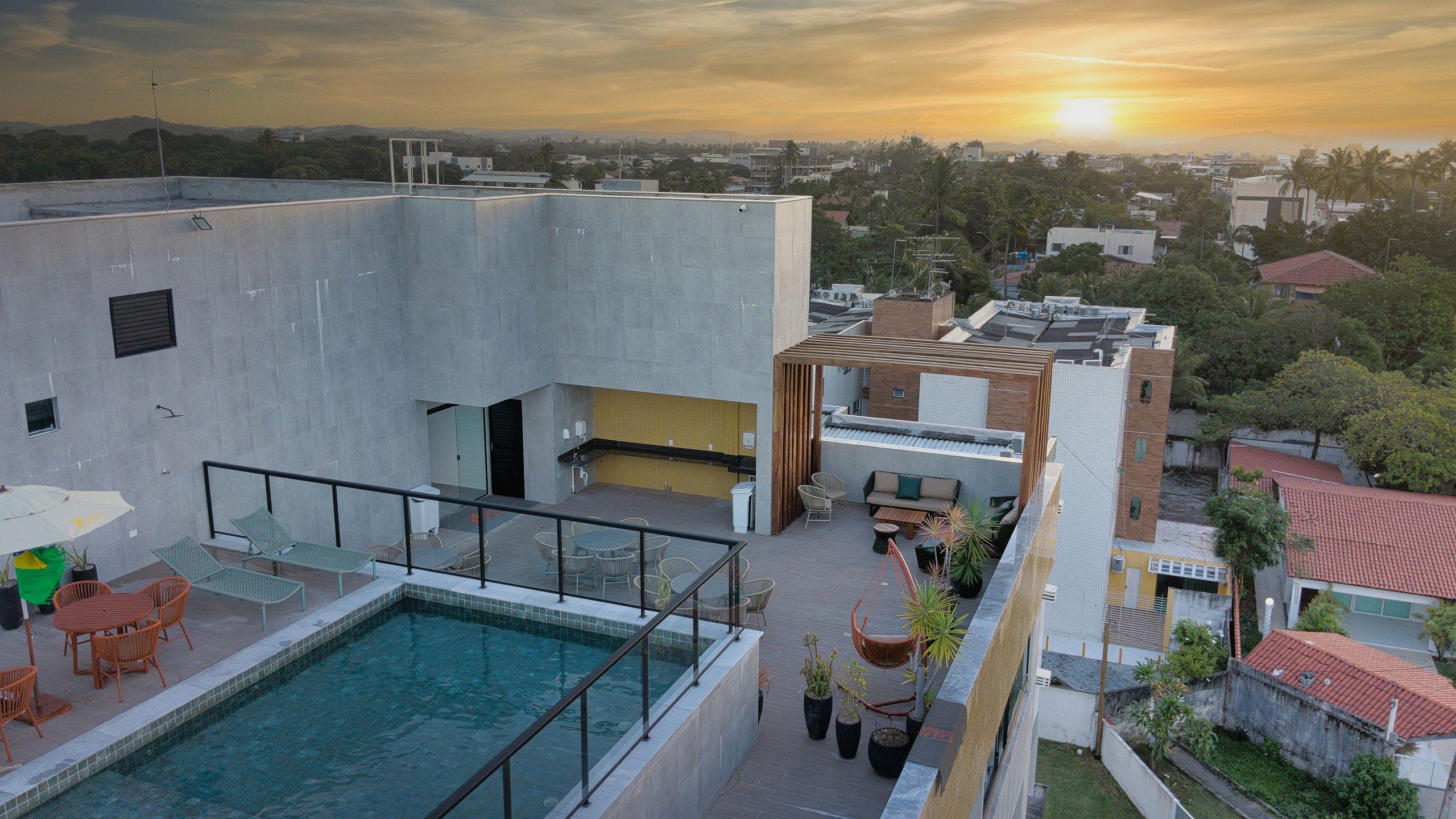 A rooftop pool area with a view of the city at sunset.
