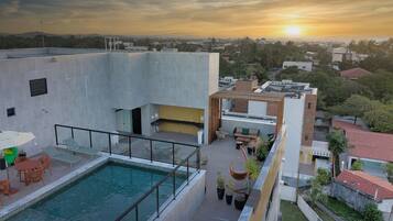 A rooftop pool area with a view of the city at sunset.