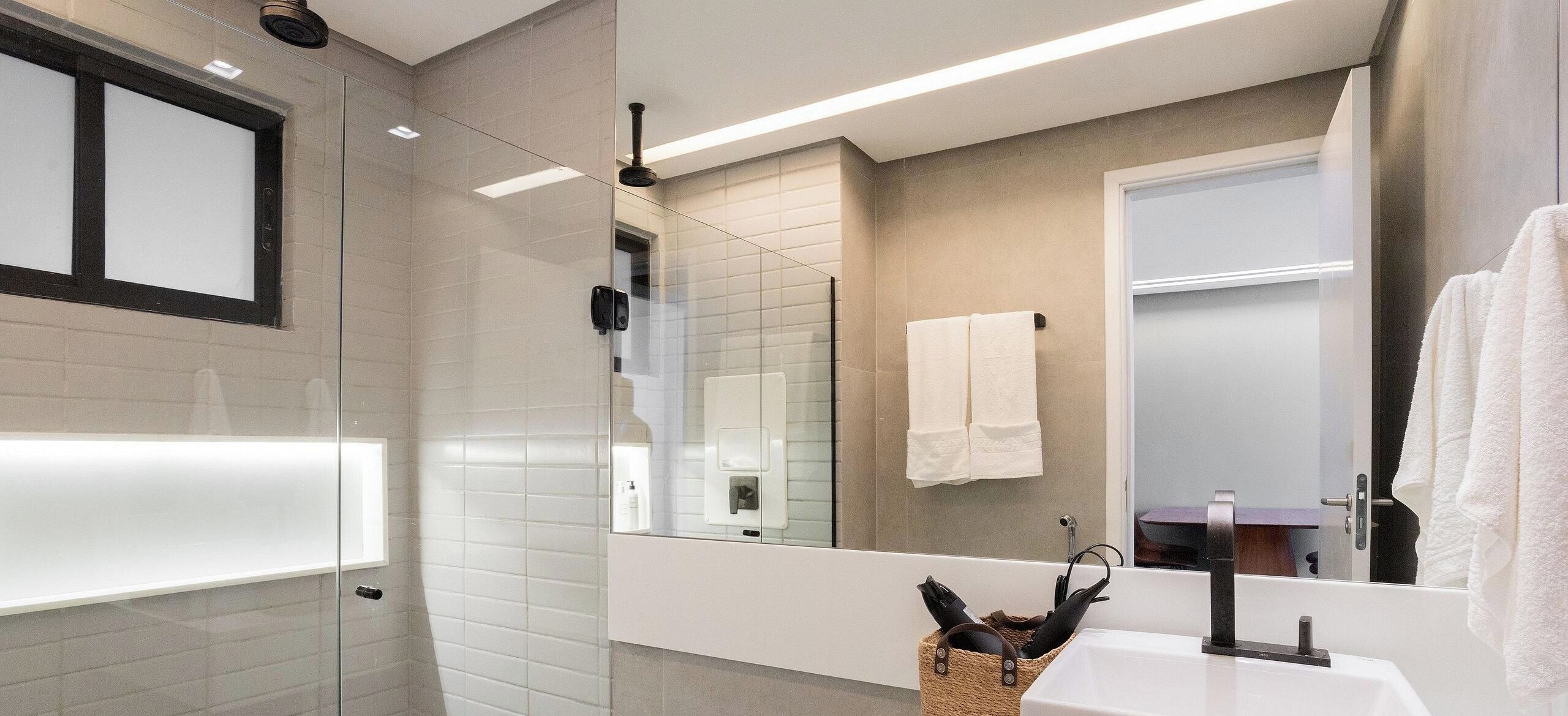 A modern bathroom with a glass shower enclosure, a white sink, and a large mirror reflecting the room.