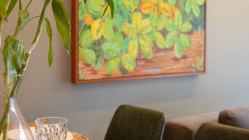 A dining table with a vase of green leaves, a glass, and a plate set for two.