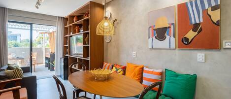 A dining area with a wooden table, chairs, a hanging light fixture, and artwork on the walls.
