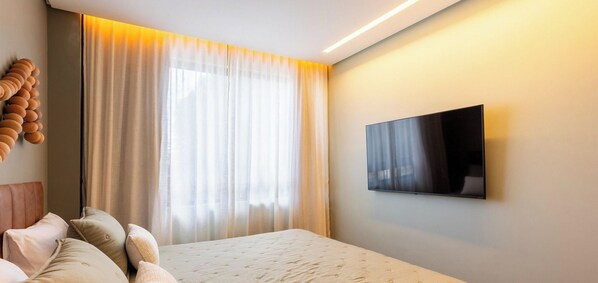 A hotel room with a bed, a TV mounted on the wall, and a large window with curtains. - Edf Tours du Porto - Centro (Ipojuca)