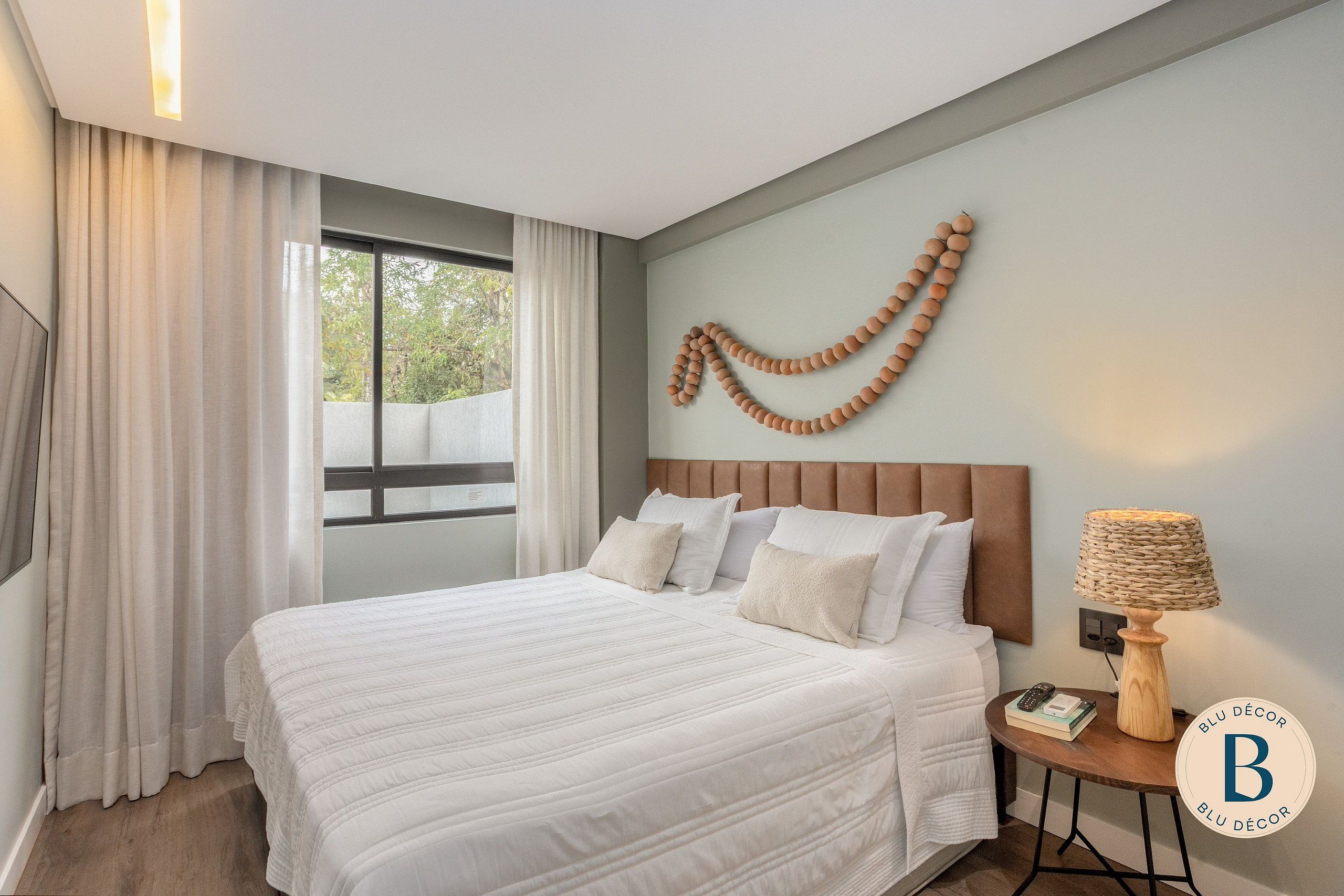 A neatly made bed with pillows, a bedside lamp, and a wall decoration.