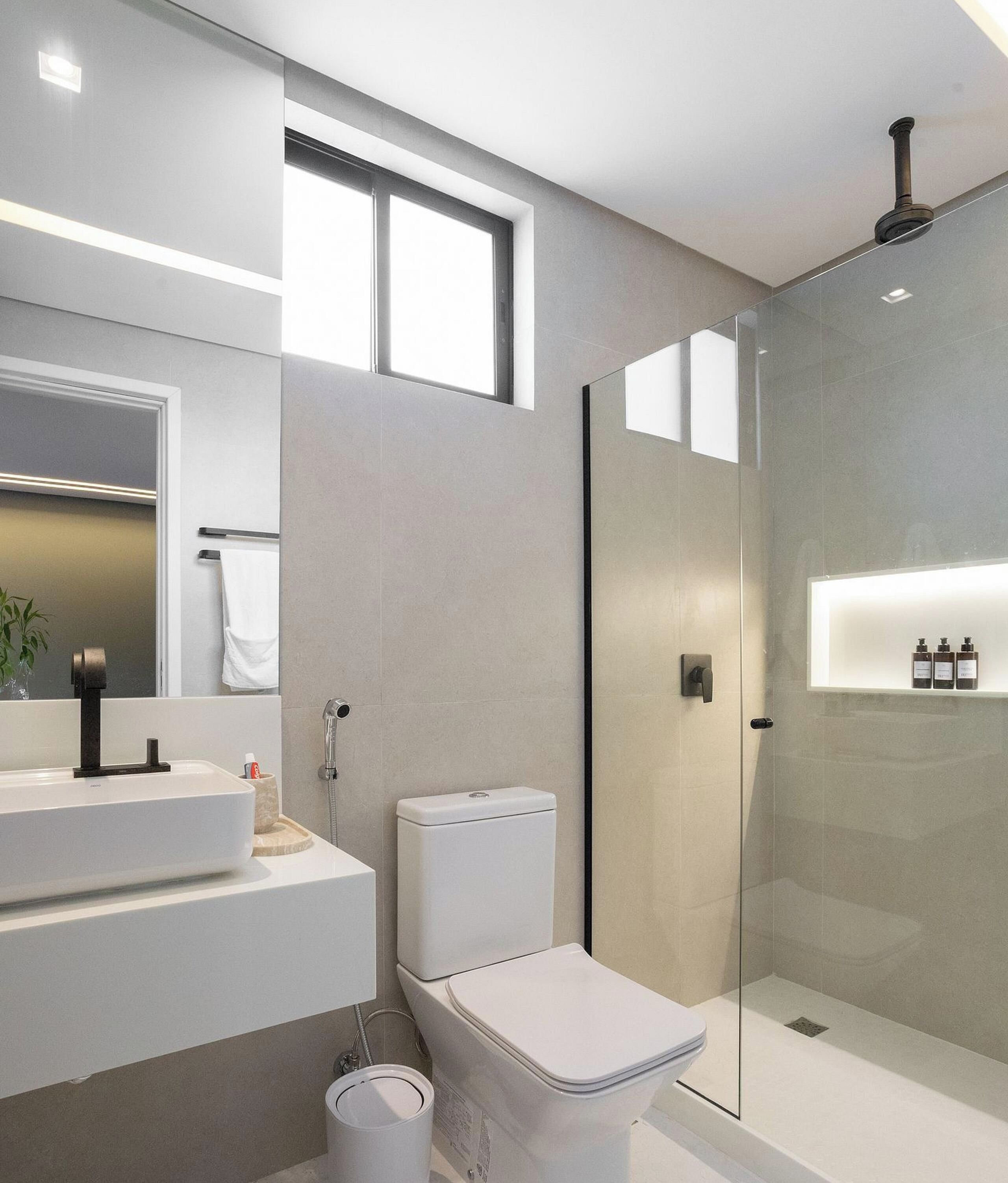 Un baño moderno con cabina de ducha de vidrio, inodoro blanco y tocador con espejo.