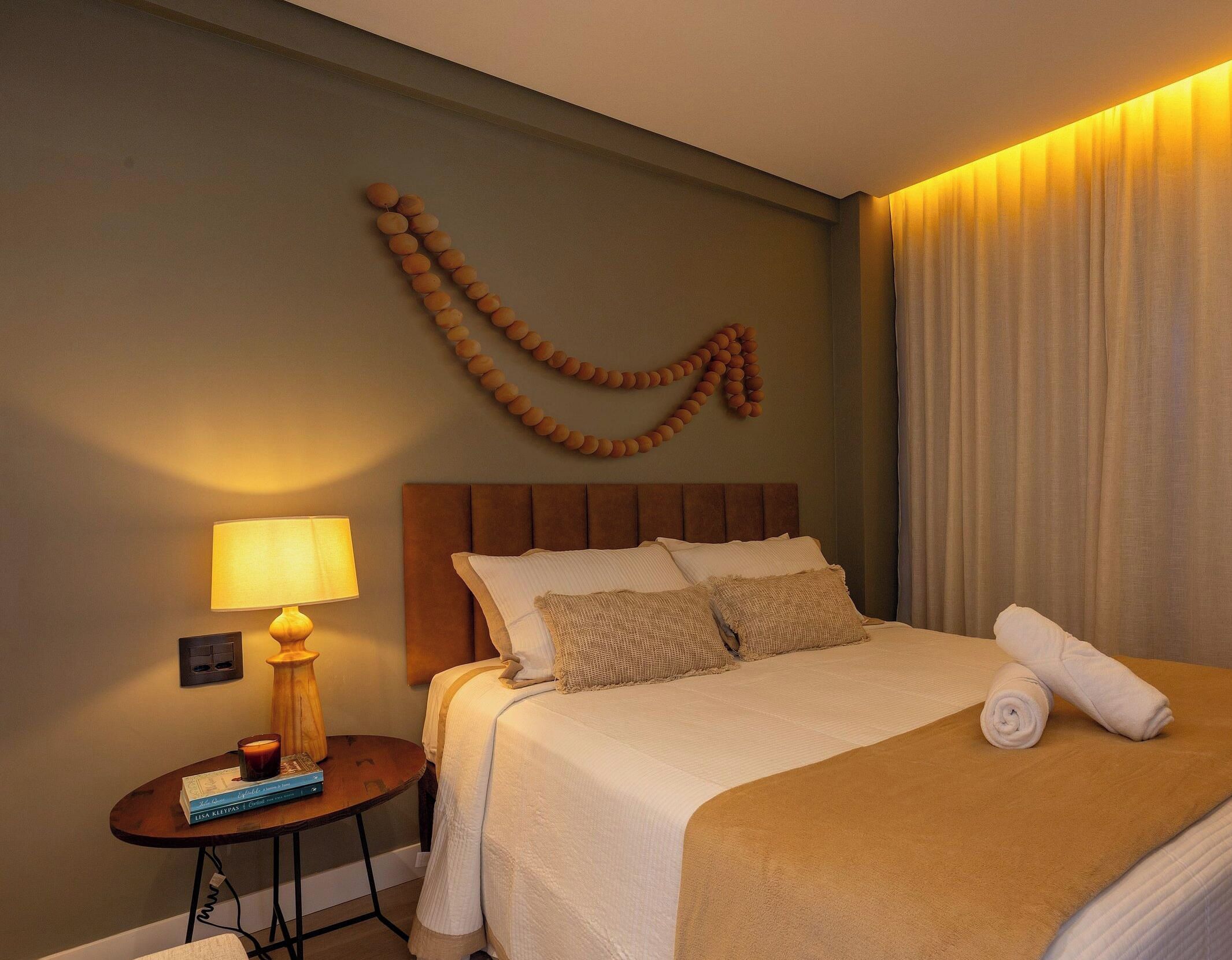 A hotel room with a bed, a nightstand, a lamp, and a wall decoration.