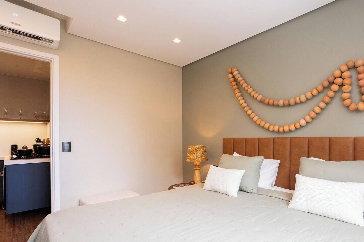 A hotel room with a bed, bedside table, lamp, and a wall decoration.